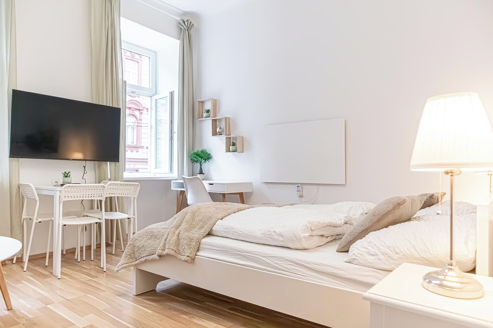 A minimalist bedroom with a bed, bedside table, and a TV mounted on the wall.