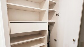 Een witte kast met meerdere planken en een stofzuiger erin.