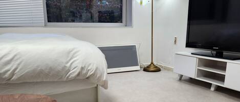 Un dormitorio moderno con cama, televisión, lámpara y mesa de madera.