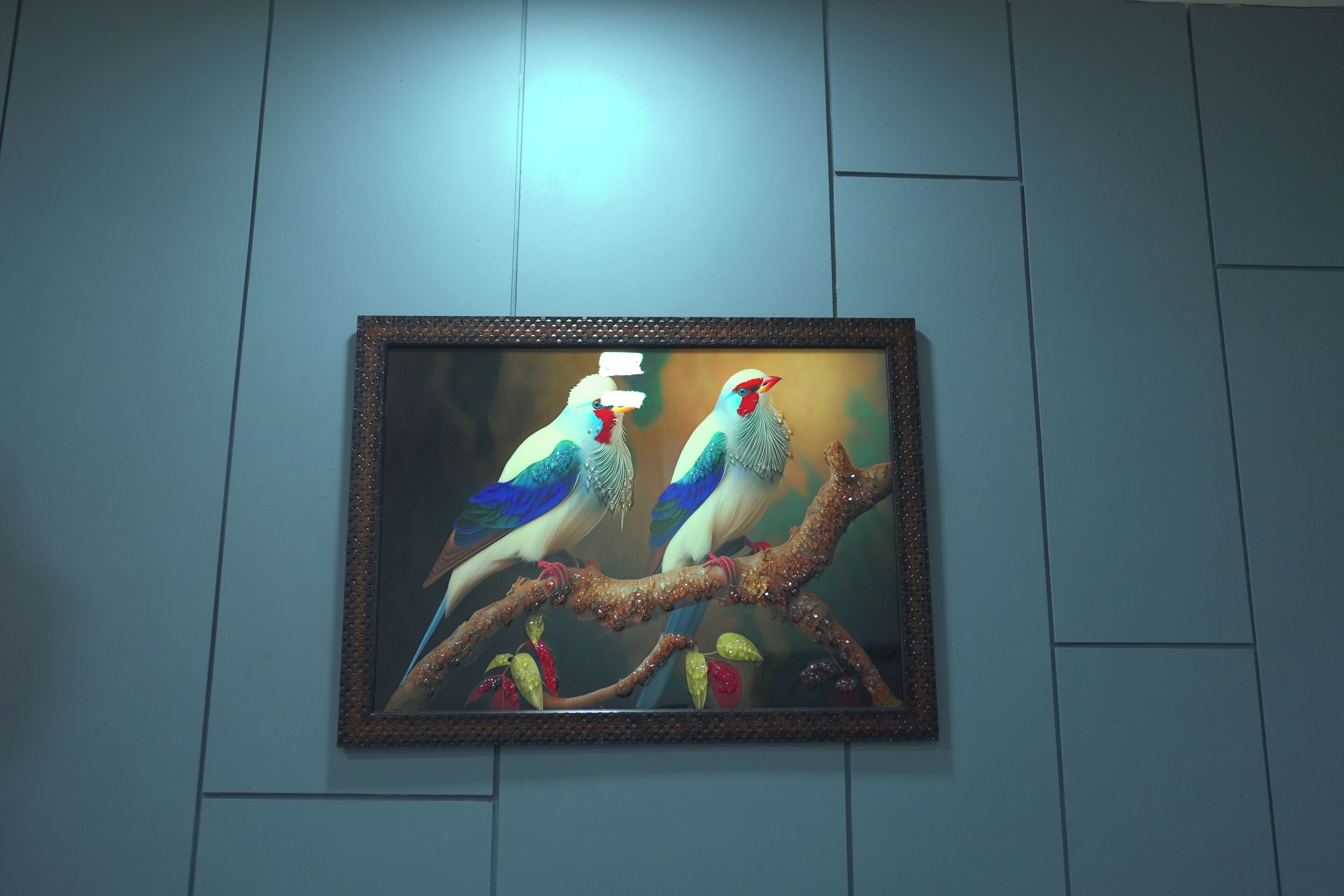 A framed artwork of two birds on a branch.