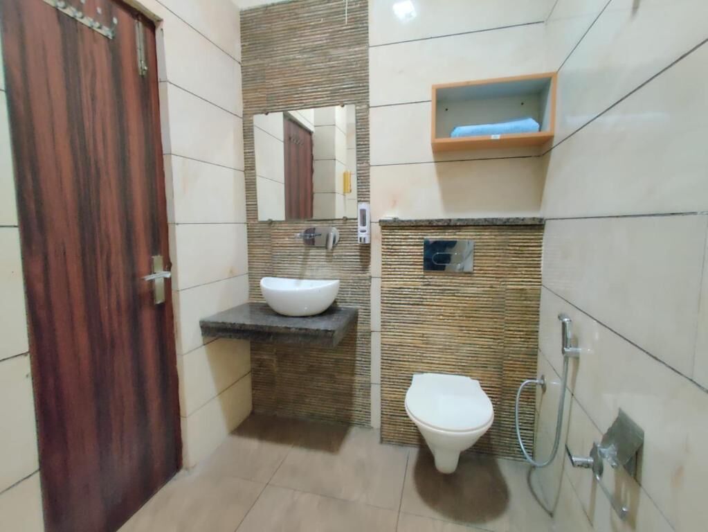 A bathroom with a wooden door, a white sink, a toilet, and a shower.