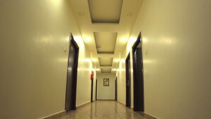 A long, well-lit hallway with marble flooring and doors on both sides. - GOLDEN GSC HOTEL (Amritsar)