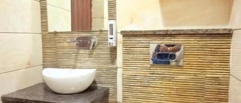 Une salle de bain avec un lavabo blanc, des toilettes, un miroir et une étagère à serviettes.
