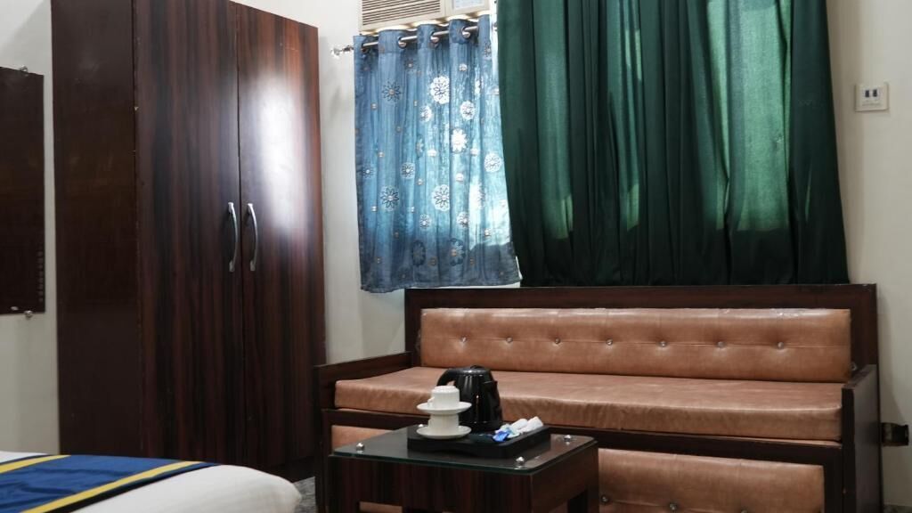 Una habitación con un armario grande, un sofá, una mesita con una tetera y una cama con edredón a rayas azul y amarillo.