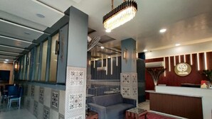 A hotel lobby with a reception desk, a seating area with a sofa and armchairs, patterned walls, and a chandelier. - GOLDEN GSC HOTEL (Amritsar)