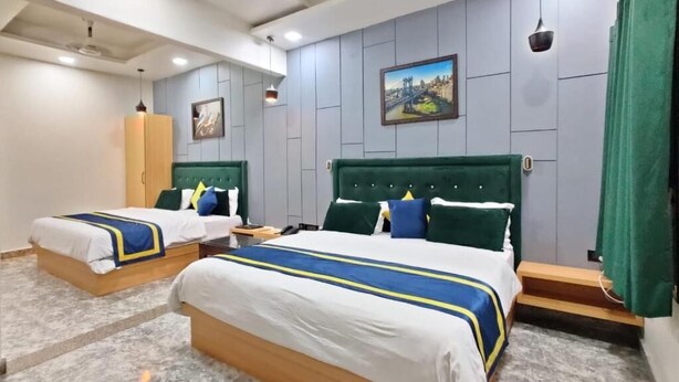 A hotel room with two beds, a green headboard, and a painting on the wall. - GOLDEN GSC HOTEL (Amritsar)