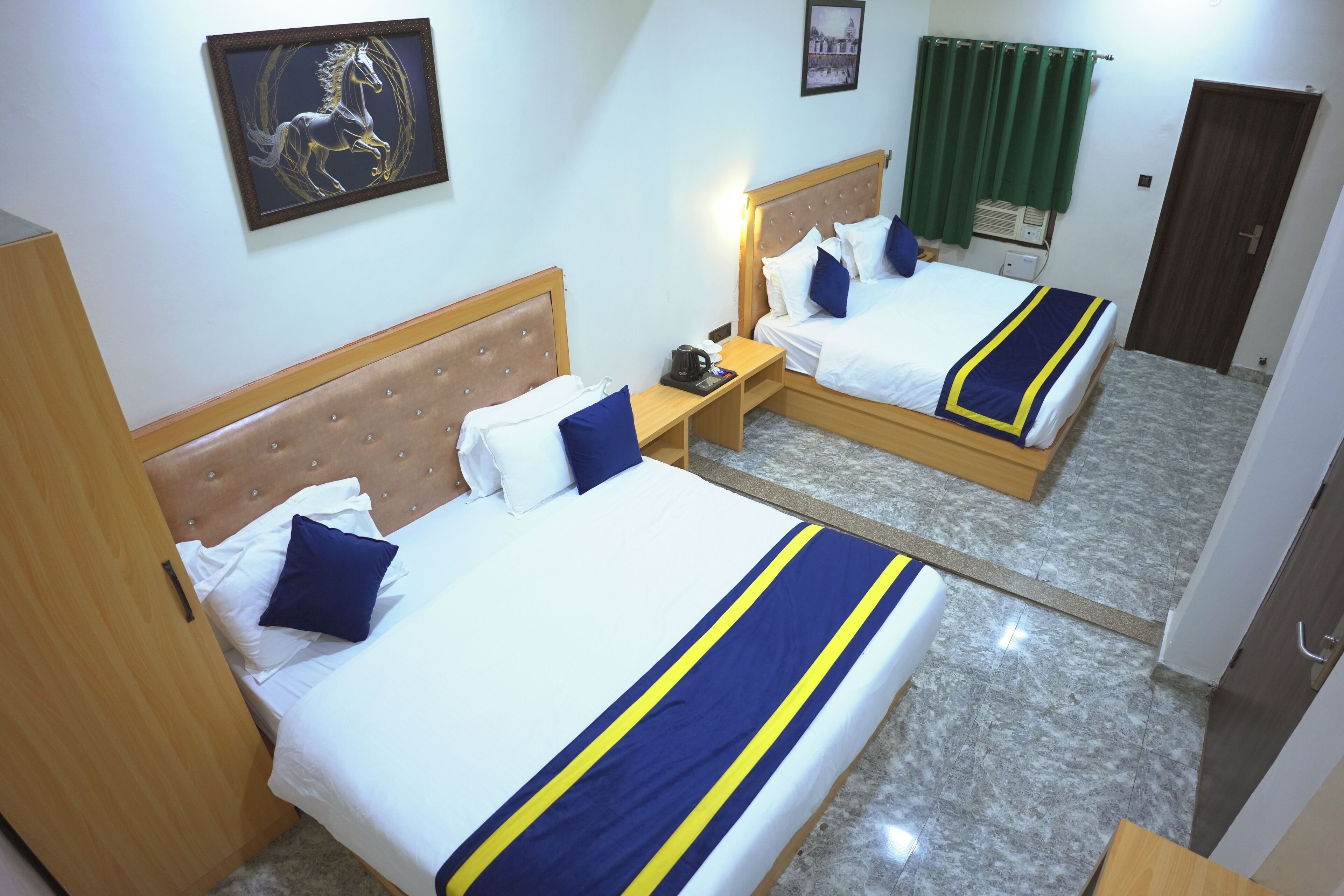 A hotel room with two beds, a mirror, a nightstand, a framed picture on the wall, and a green curtain.