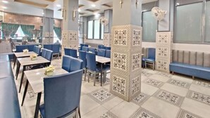 A restaurant with blue booths, patterned pillars, and a tiled floor. - GOLDEN GSC HOTEL (Amritsar)