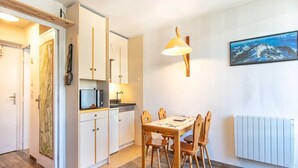 A compact kitchen with white cabinets, a microwave, and a sink. There's a dining table with chairs and a painting on the wall. - Cosy Mountain Retreat for 4 Guests (Villard-de-Lans)