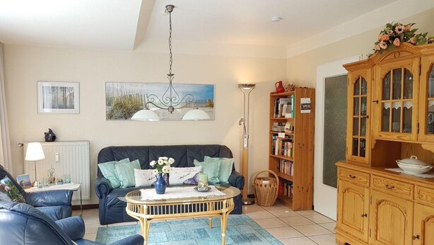 A living room with a sofa, a coffee table, a bookshelf, and a cabinet. - Ferienwohnung in St. Peter-ording (St. Peter-Ording)