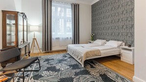 A modern bedroom with a large bed, a bedside table, a mirror, and a floor lamp. - Imperial Apartments - Nadmorski Park (Sopot)