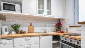A modern kitchen with white cabinets, a wooden countertop, a microwave, a sink, and an oven. - Imperial Apartments - Nadmorski Park (Sopot)
