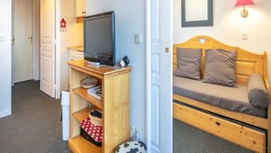 A room with a wooden TV stand, a sofa bed, and a wall-mounted lamp. - Mountain Hideaway in Risoul (Risoul)