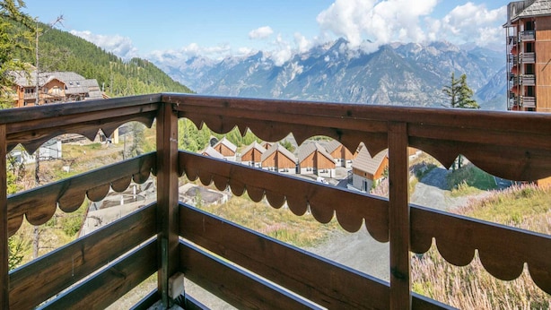 A wooden balcony with a view of mountain houses and a mountain range. - Mountain Hideaway in Risoul (Risoul)