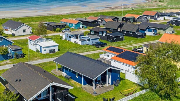Een kustdorp met verschillende kleine huizen, waarvan sommige garages hebben, en een strand op de achtergrond.