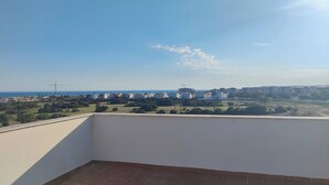 Een balkon met een helder uitzicht over een stadsgezicht, inclusief gebouwen en een verre kustlijn.