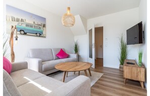 Un salon moderne avec un canapé, une table basse et un tableau représentant un fourgon.