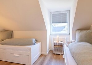 A bedroom with a loft bed, a bedside table with a lamp, and a radiator.