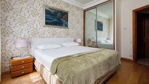 A bedroom with a bed, a nightstand, a lamp, a painting on the wall, and a mirror.