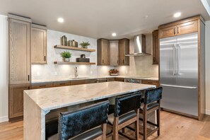 Una cocina moderna con armarios de madera, un refrigerador de acero inoxidable y una encimera de mármol.