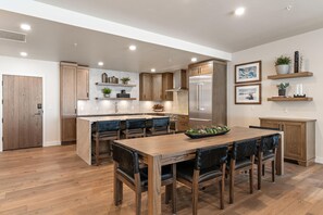 Una cocina moderna con armarios de madera, una isla central y un comedor con mesa y sillas de madera.