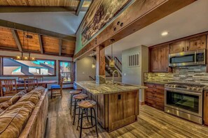 A modern kitchen with a central island, stainless steel appliances, and a wooden ceiling. - Lakeside Haven by Heavenly Sand (South Lake Tahoe)