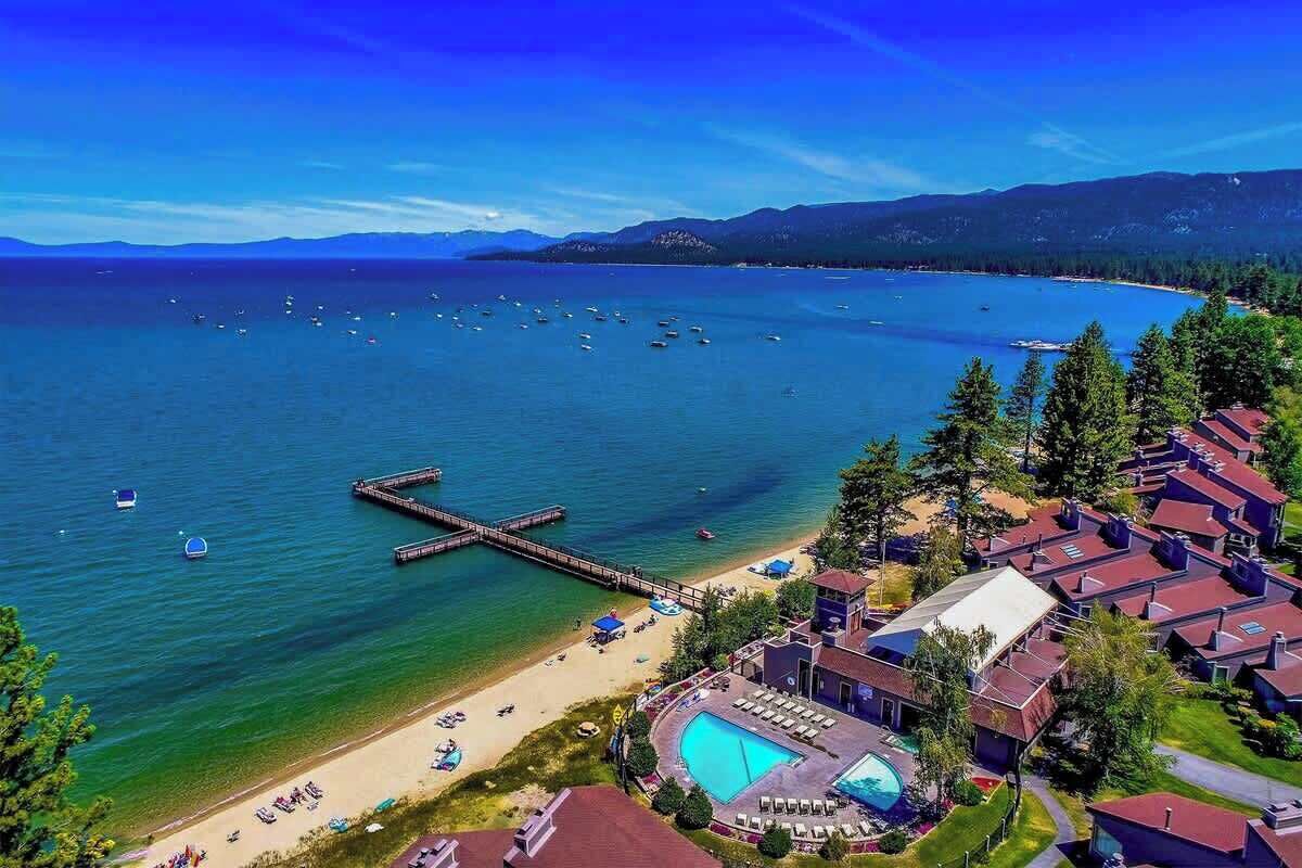 A coastal resort with a swimming pool, beach, and pier.