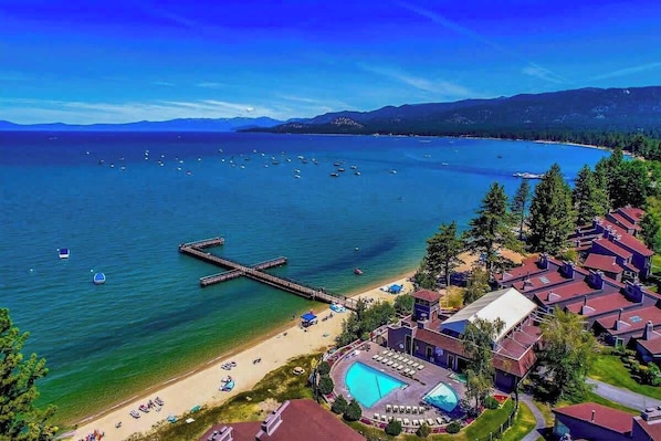 A coastal resort with a swimming pool, beach, and pier.