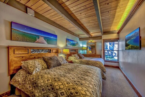 A hotel room with two beds, wooden headboards, and artwork on the walls.