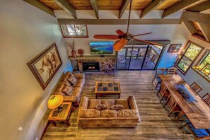 A spacious living room with a fireplace, a sofa, a dining table, and a ceiling fan.