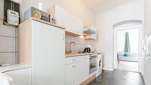 A modern kitchen with white cabinets, a built-in oven, and a washing machine.
