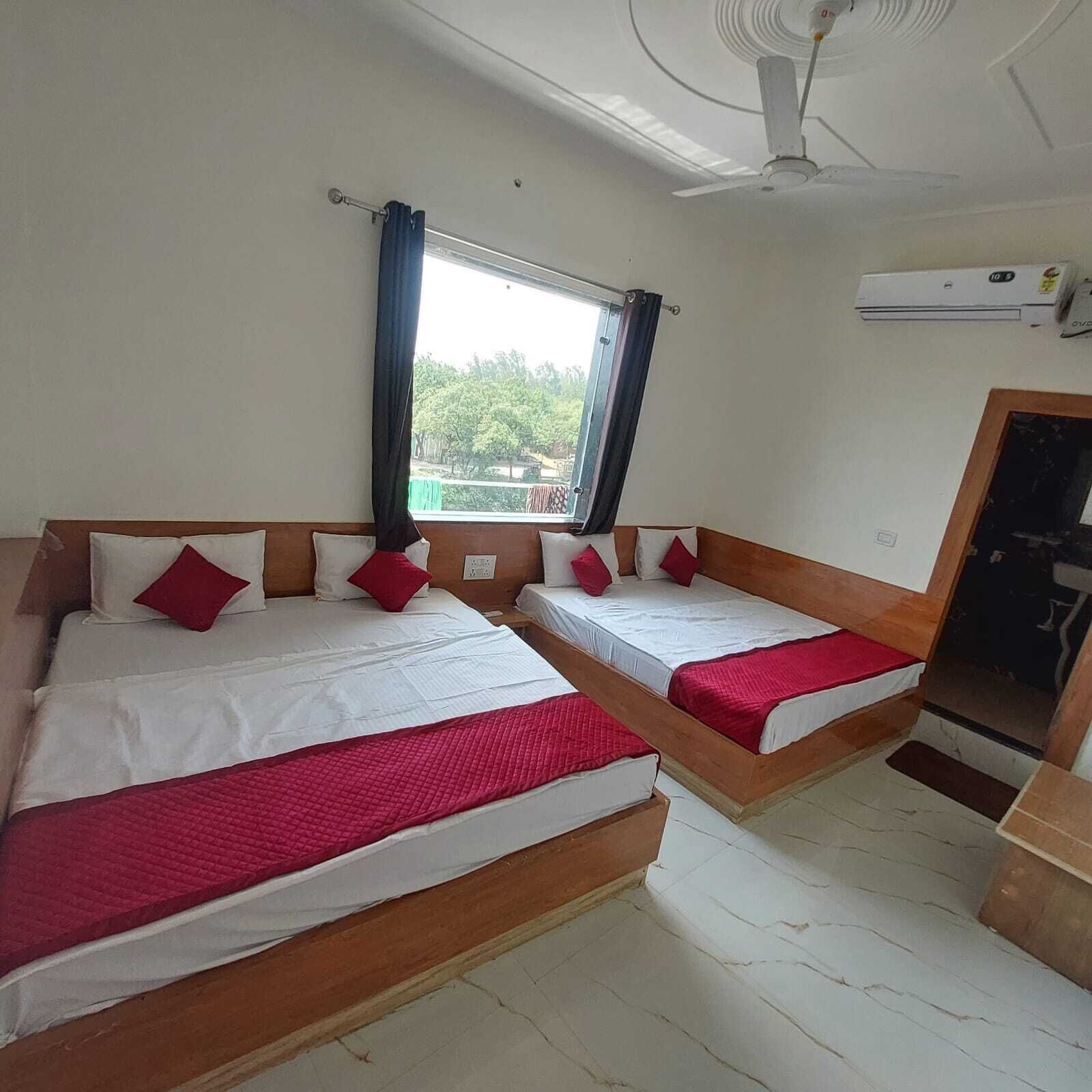 A hotel room with two beds, a window with curtains, a ceiling fan, and an air conditioning unit.