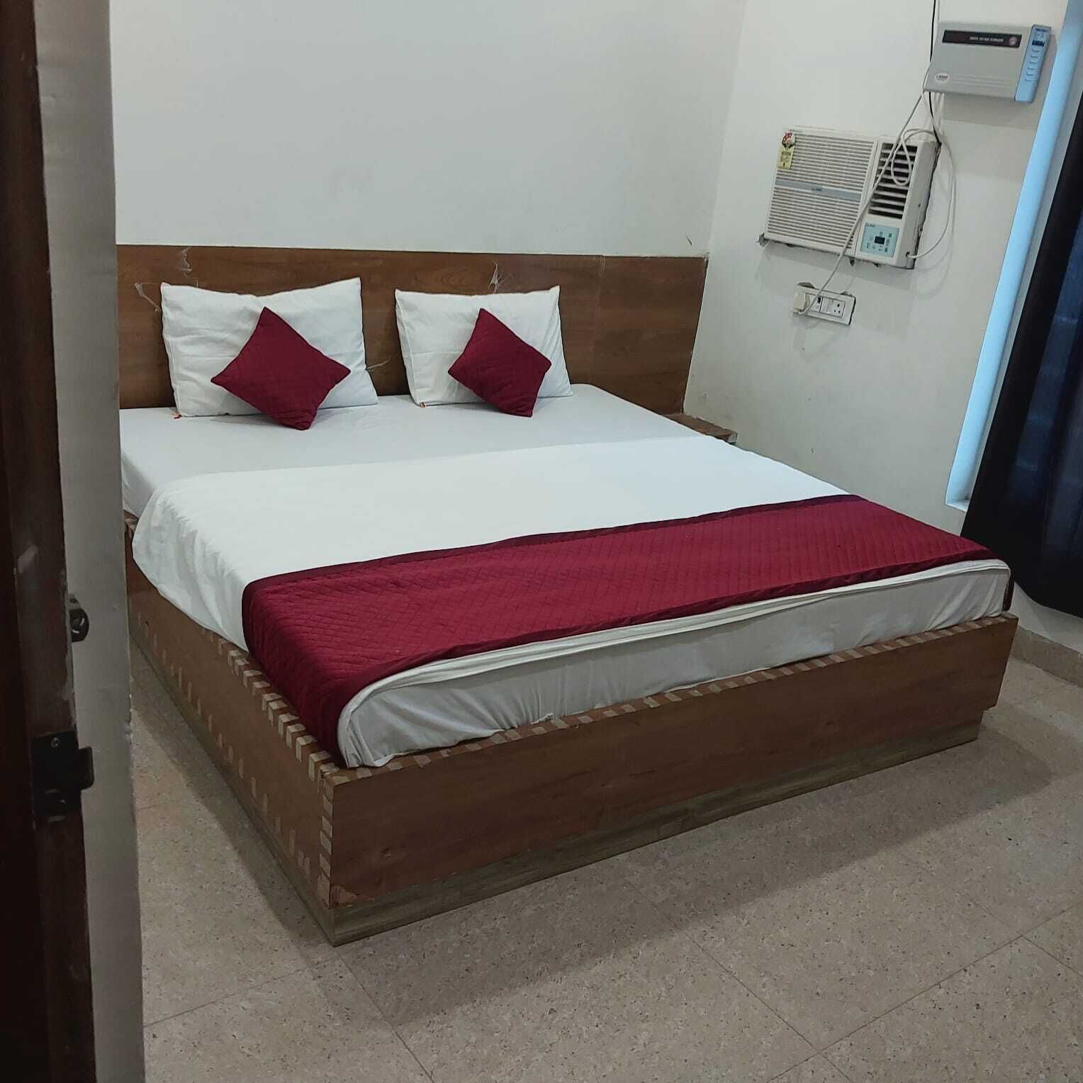 A bed with a wooden frame, white bedding, and a red blanket.
