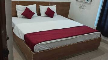 A bed with a wooden frame, white bedding, and a red blanket.