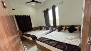 A room with two beds, a ceiling fan, and a window with curtains.