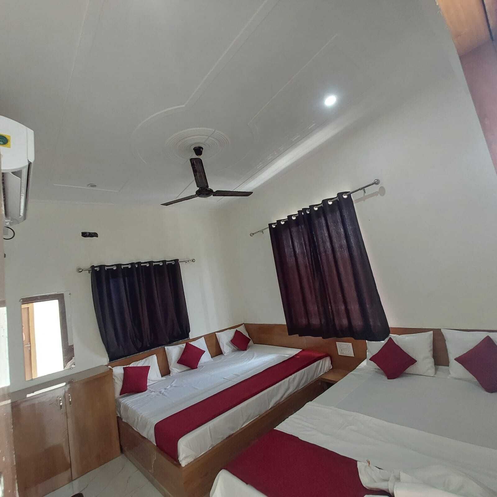 A hotel room with two beds, dark curtains, a ceiling fan, and a window.