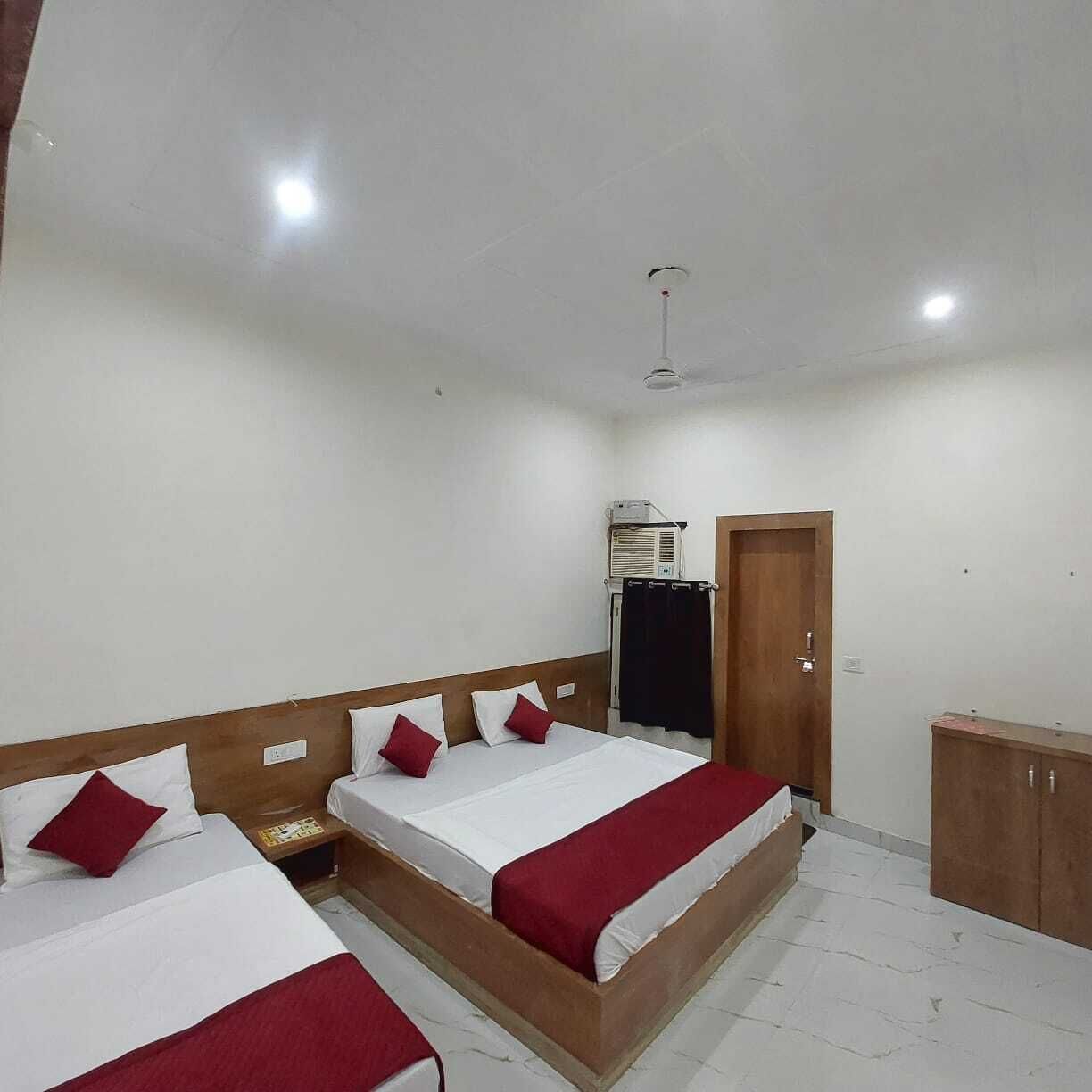 Quarto de hotel com duas camas, um guarda-roupa, um ventilador de teto e um ar condicionado.