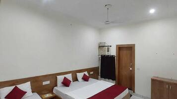 Quarto de hotel com duas camas, um guarda-roupa, um ventilador de teto e um ar condicionado.