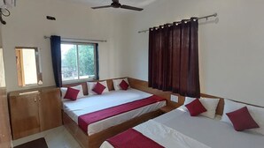 A hotel room with two beds, a ceiling fan, a window with curtains, and a wooden wardrobe.