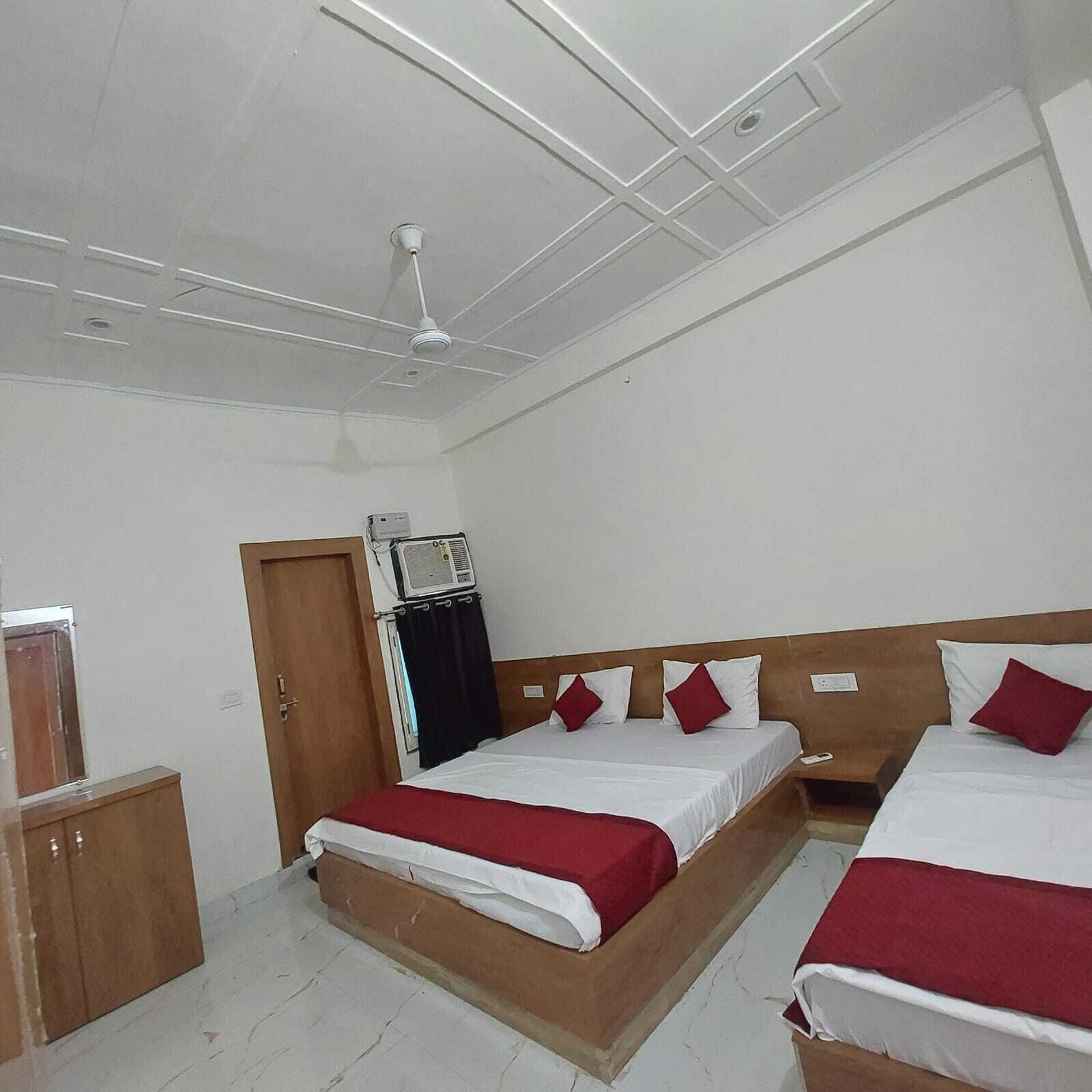 Quarto de hotel com duas camas, um guarda-roupa, um ventilador de teto e um ar condicionado.