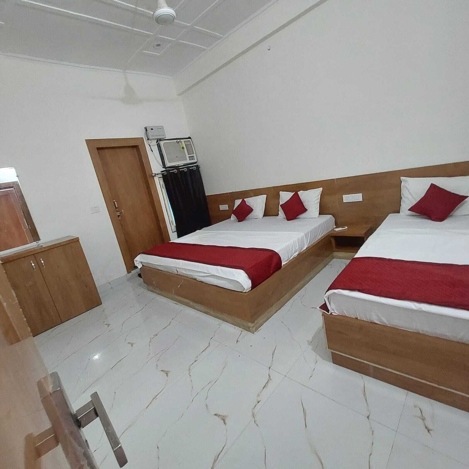 A hotel room with two beds, a wardrobe, and an air conditioning unit.