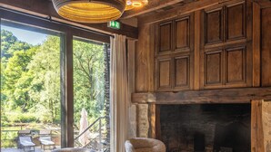 A rustic interior with wicker furniture, a fireplace, and a view of the outdoors. - Le Moulin de Cambelong (Conques-en-Rouergue)