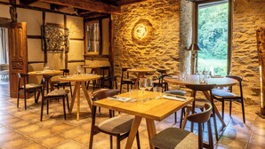 A rustic dining area with stone walls, wooden tables, and chairs. - Le Moulin de Cambelong (Conques-en-Rouergue)