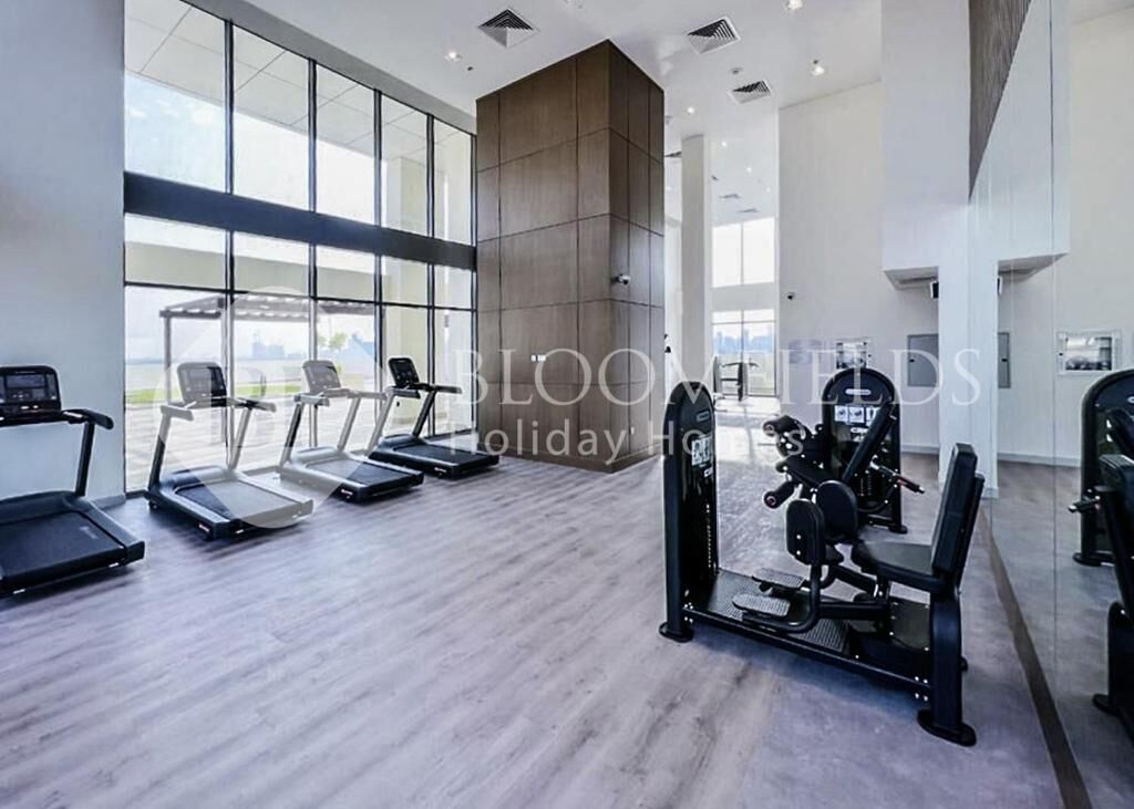 A modern gym with treadmills, elliptical machines, and weight equipment.