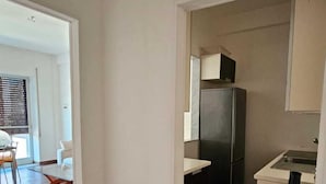 A kitchen with a refrigerator, a sink, and a countertop. There is a dining area with a table and chairs visible in the background. - CconfortHotels Dimora Cavour (Bari)