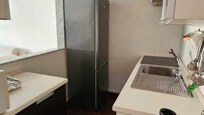 A compact kitchen with a refrigerator, sink, and a white countertop. - CconfortHotels Dimora Cavour (Bari)