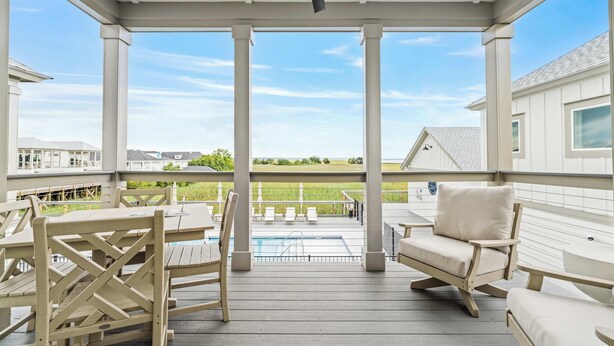 Une terrasse extérieure couverte, aménagée avec du mobilier en bois, une piscine et une vue sur les environs.