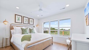 Une chambre à coucher moderne avec un lit en bois, un bureau et une grande fenêtre donnant sur l’extérieur.