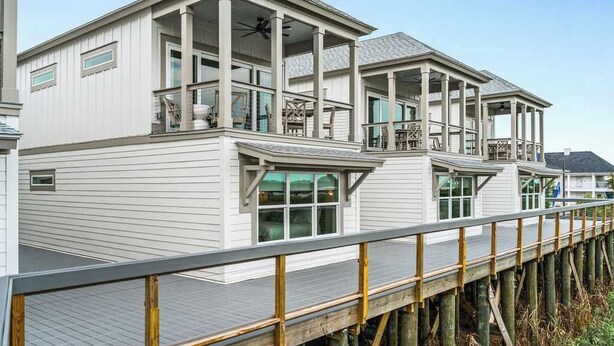 Une maison située sur la côte, dotée d’une terrasse en bois et d’un balcon.