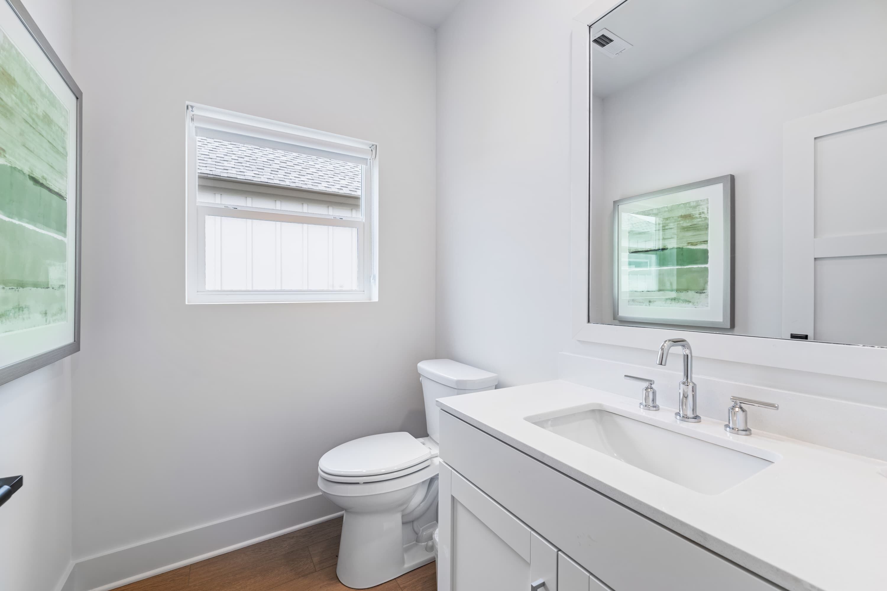 A modern bathroom with a toilet, sink, and window.